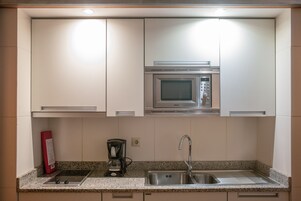 A kitchen with white cabinets, a Bosch microwave, a coffee maker, and a sink.