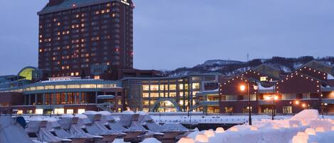 A hotel with multiple floors, a large building with a prominent sign, and a marina with boats covered in snow.