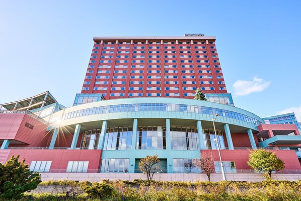 A multi-story hotel with a central atrium, large windows, and a flat roof.