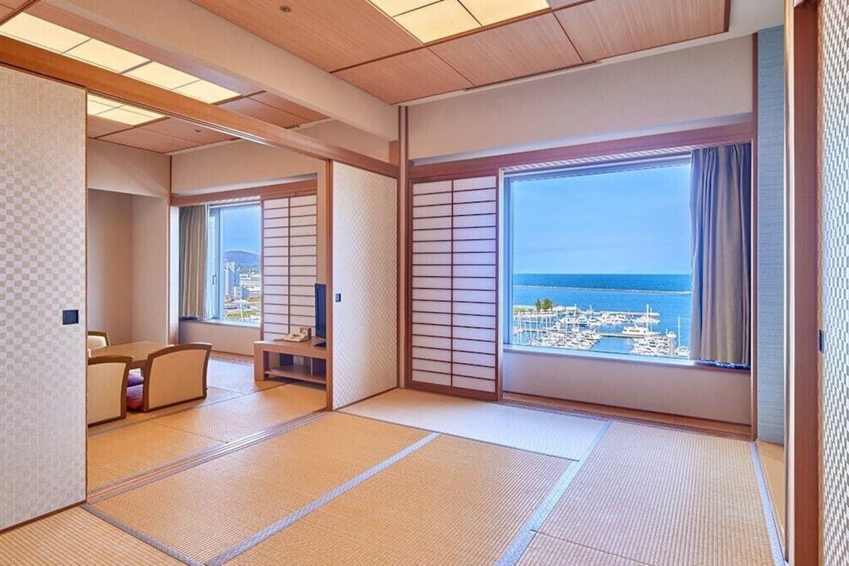 Una habitación japonesa tradicional con suelo de tatami, puertas correderas y vista al mar.