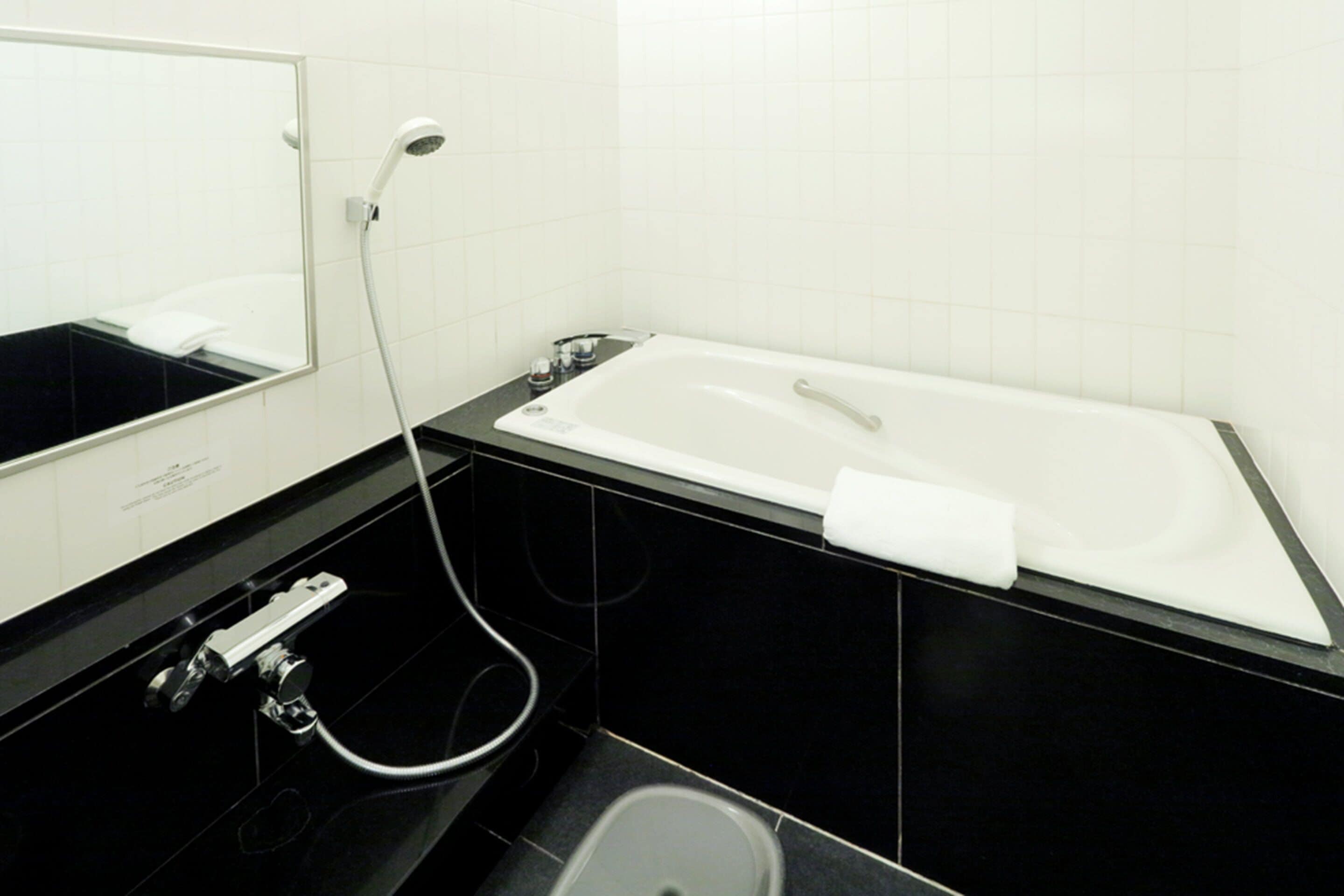 Une salle de bain moderne avec une baignoire blanche, un lavabo noir et un miroir.