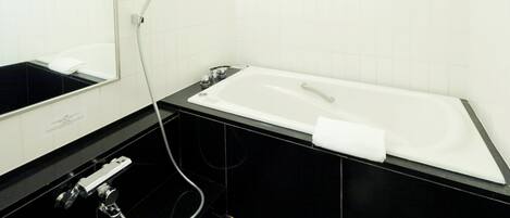 A modern bathroom with a white bathtub, a black sink, and a mirror.