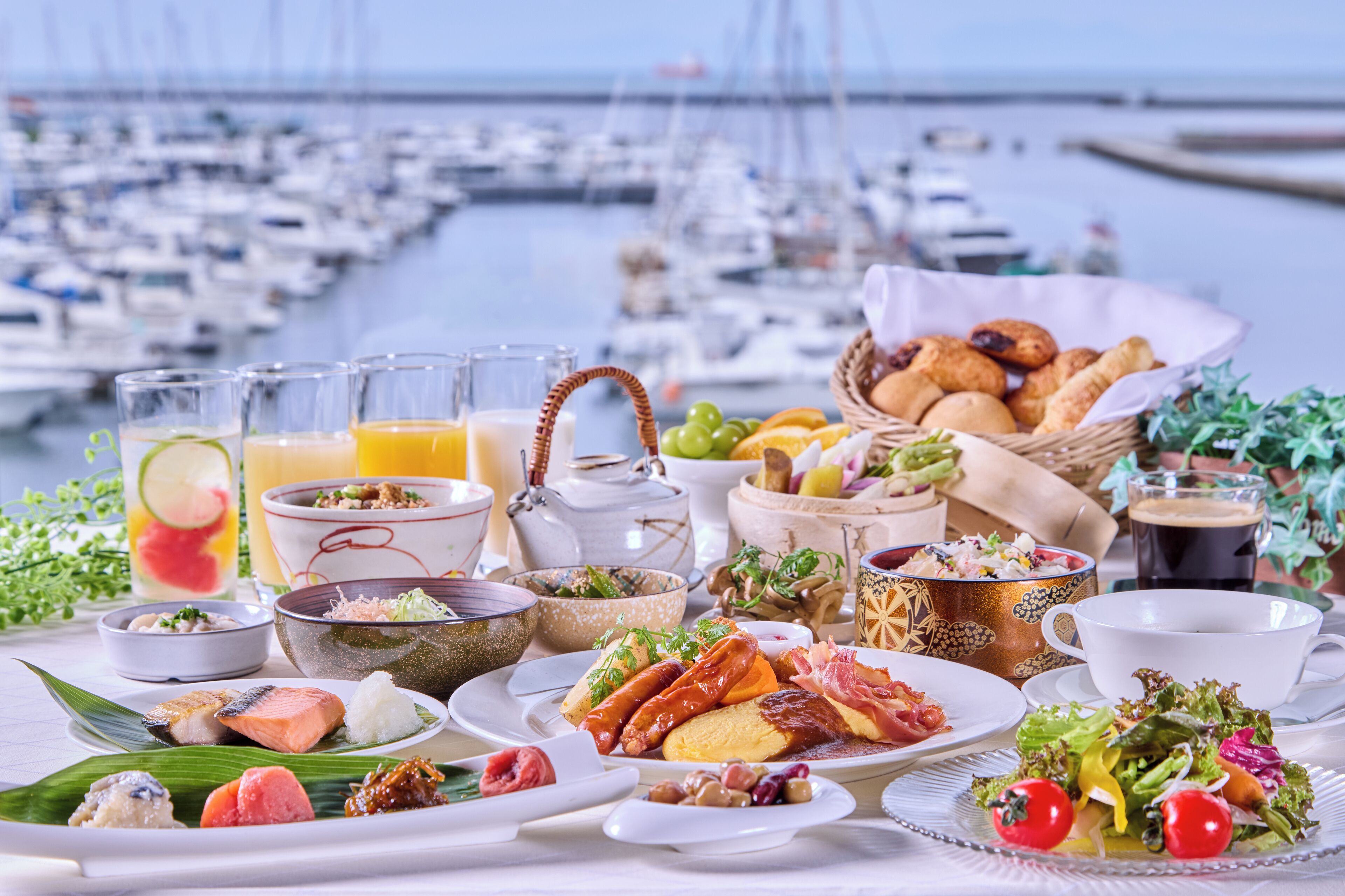 A table set with various dishes, including seafood, bread, and vegetables, with a marina view in the background.
