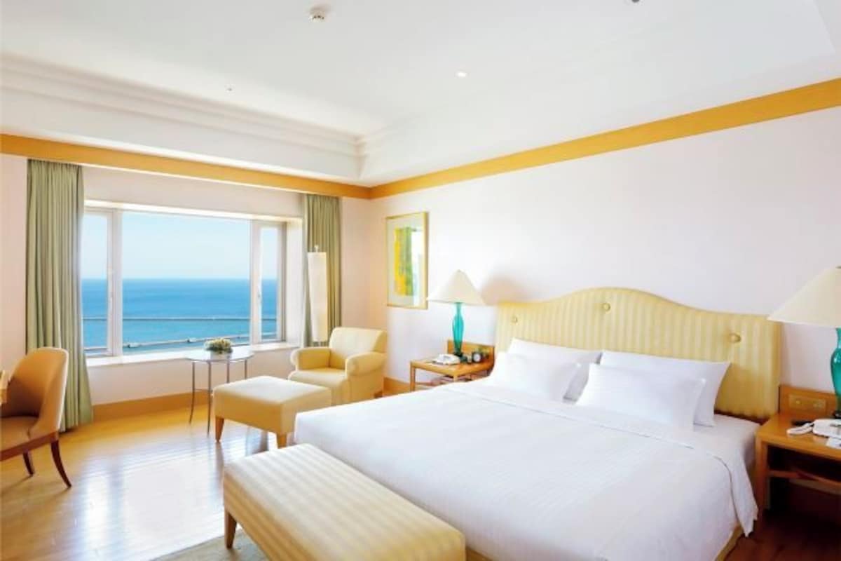 Habitación de hotel con una cama grande, un escritorio, una silla y vista al océano.