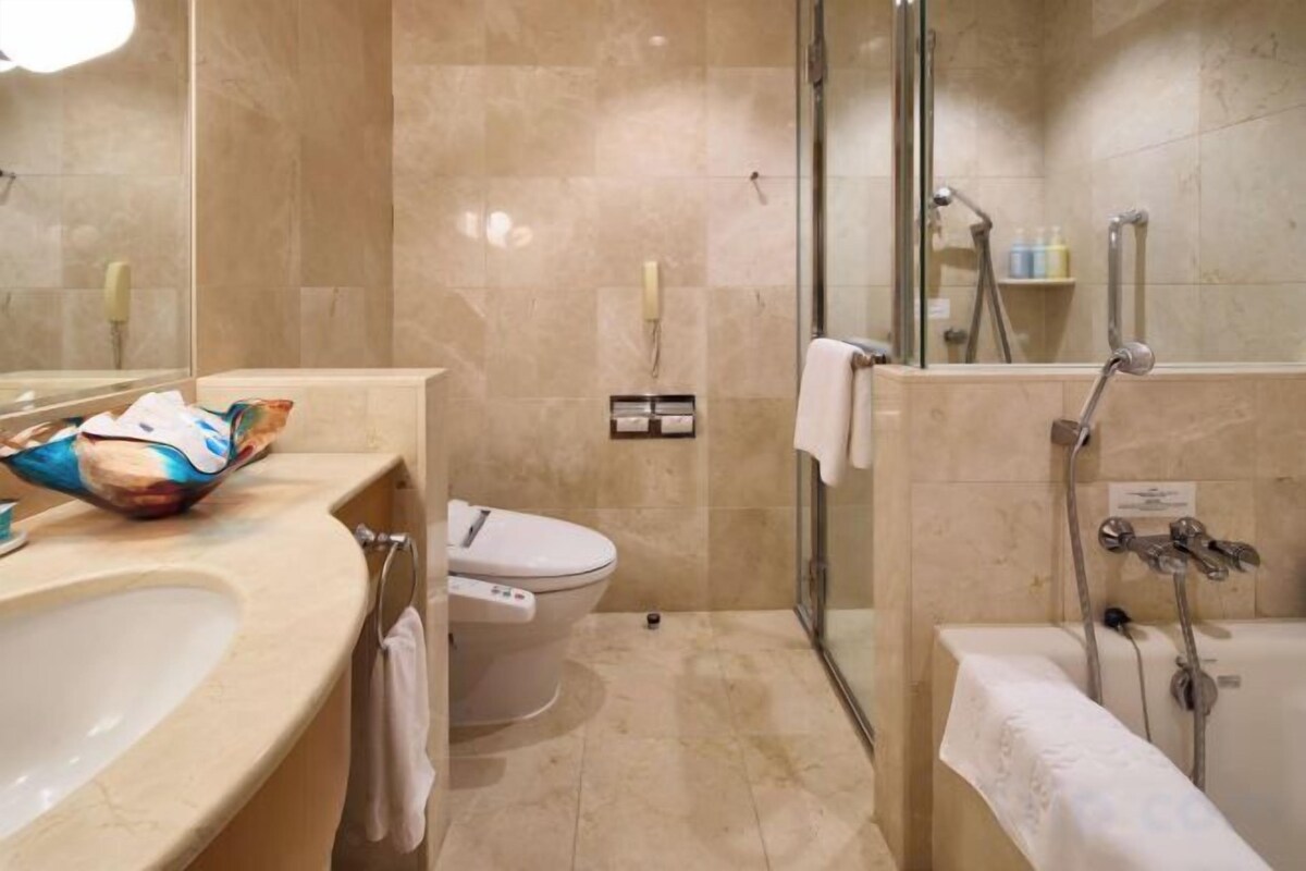 A bathroom with a sink, toilet, shower, and glass-enclosed shower stall.