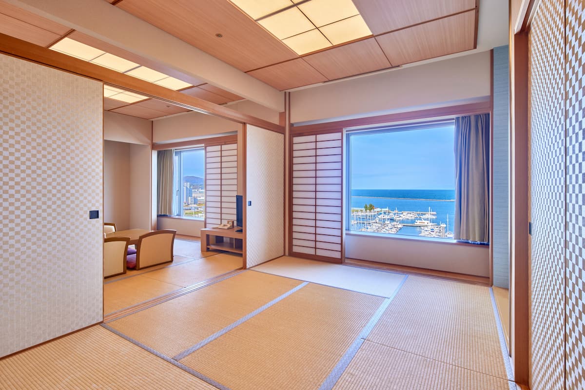 A traditional Japanese room with tatami flooring, sliding doors, and a view of the sea.