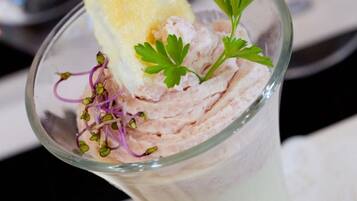 A clear glass with a layered drink, garnished with parsley and a lemon slice.
