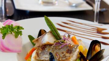 A dining table with a plate of seafood, a glass of white wine, and a dessert drink.