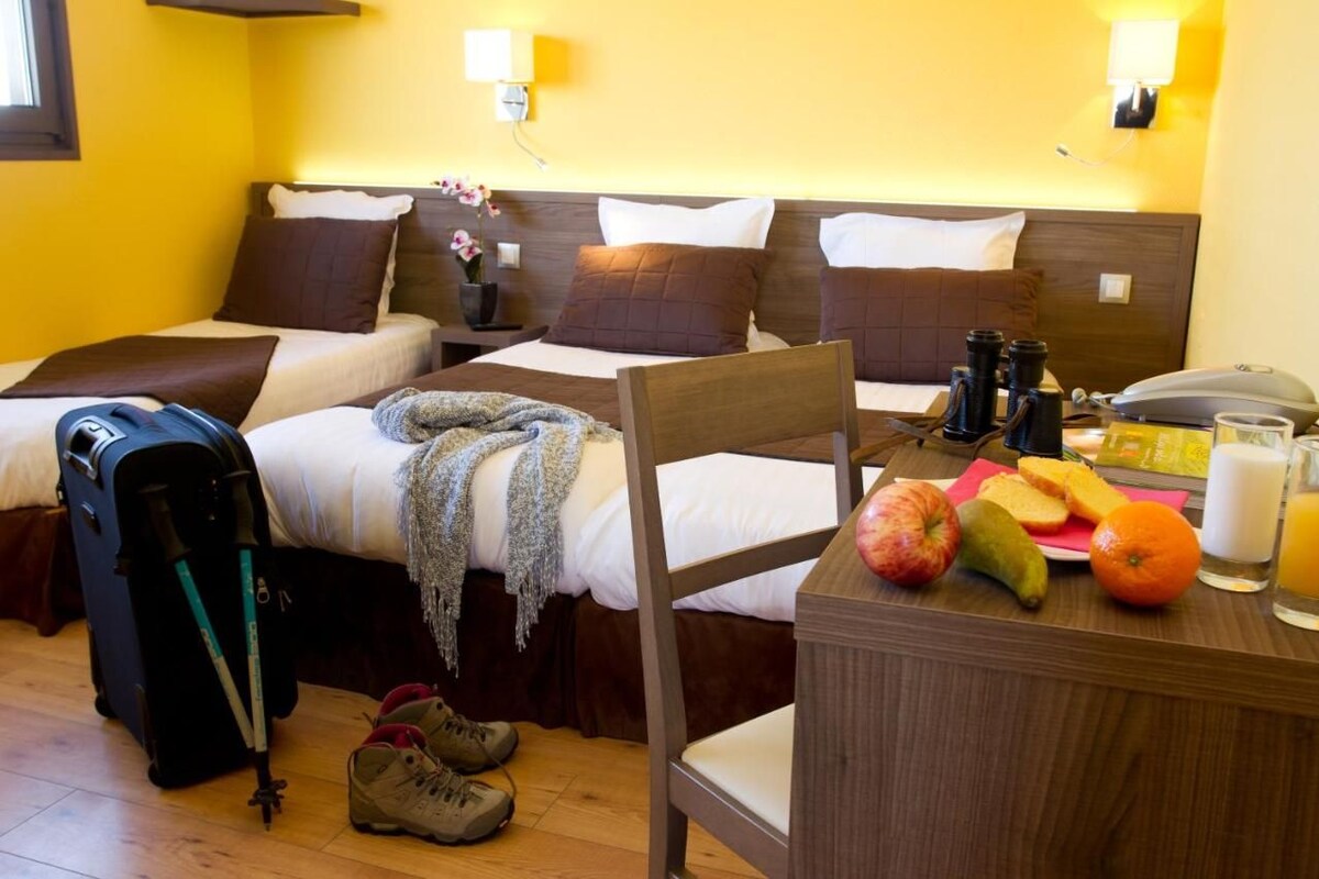 Una habitación de hotel con dos camas, un escritorio con desayuno, una maleta y un par de zapatos.