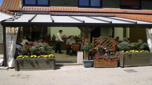 Un espace extérieur abrité, aménagé avec des tables et des chaises, et entouré de jardinières fleuries.