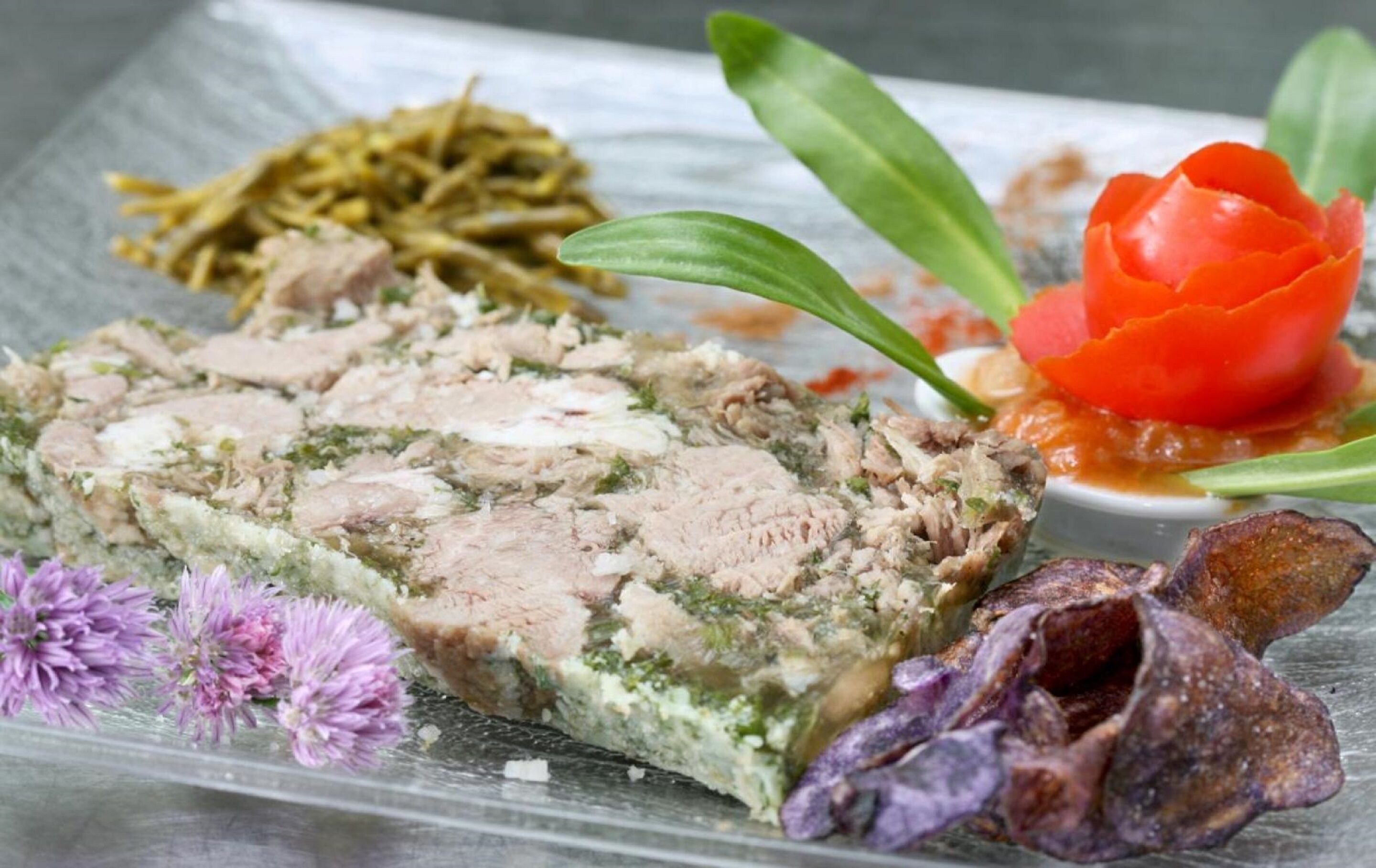 A dish with meat and greens, accompanied by a side of pickled vegetables and a decorative flower.
