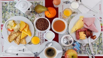 Una mesa de desayuno con platos de comida, incluyendo tostadas, huevos, tocino y fruta.