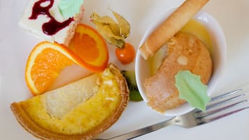 A plate with a slice of quiche, a piece of meat, a small bowl of sauce, and a piece of bread.