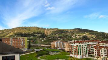 A residential area with apartment buildings, a park, and a hilly backdrop.