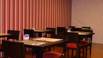 A dining area with striped wallpaper, wooden tables, and chairs.