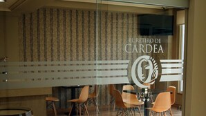 Un vestíbulo de hotel con un panel de vidrio, suelo de madera y sillas naranjas.