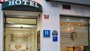 Entrada de hotel con puerta de cristal, mostrador de recepción en el interior y señal que indica acceso para personas con movilidad reducida.