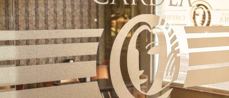 A hotel interior with a wooden floor, a glass partition, and a sign reading "EL RETIRO DE CARDEA HOTEL".