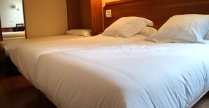 A hotel room with two single beds, wooden headboard, and a small bedside table. - El Retiro de Cardea (Oviedo)