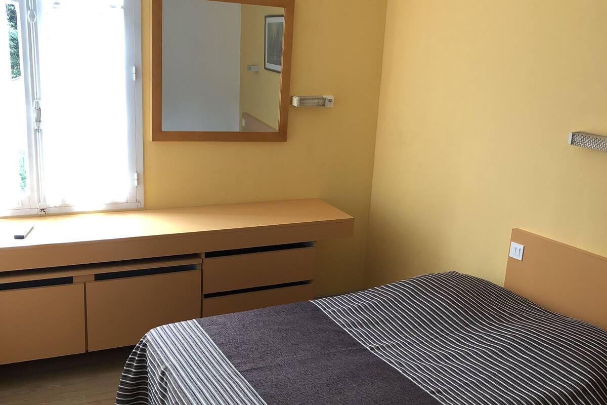 Un dormitorio con cama, cómoda, espejo y ventana.