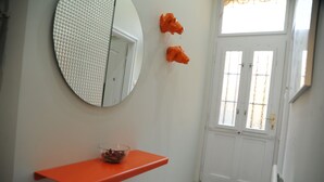 Ein Badezimmer mit einer weißen Tür, einem runden Spiegel und einem orangen Waschbecken.