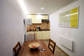 Μια μικρή, λειτουργική κουζίνα με τραπέζι φαγητού, καρέκλες, κουζίνα και έναν χάρτη στον τοίχο.