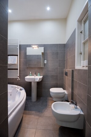Une salle de bain moderne équipée d’une baignoire, d’un lavabo, d’un bidet et d’un miroir.