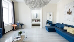 Una sala de estar moderna con un sofá azul, una mesa de centro de vidrio y una lámpara de techo original.