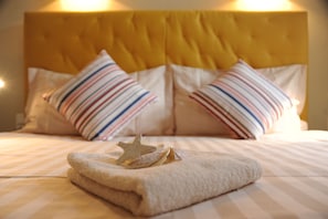 Un lit avec des oreillers à rayures, une décoration en forme d’étoile et une serviette soigneusement pliée.