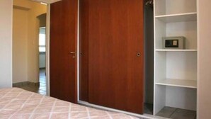 A bedroom with a bed, a wardrobe, and a shelf unit.