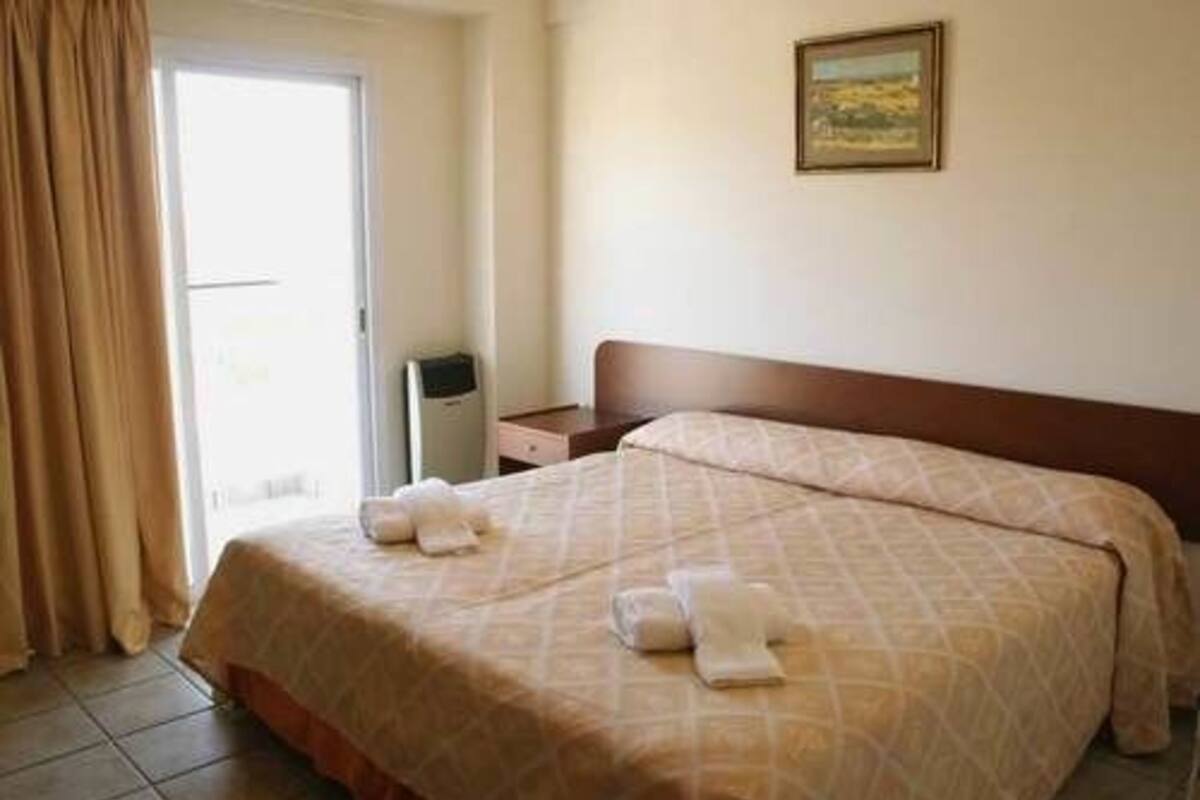 Una habitación de hotel con una cama, una mesita de noche, una lámpara y un cuadro en la pared.