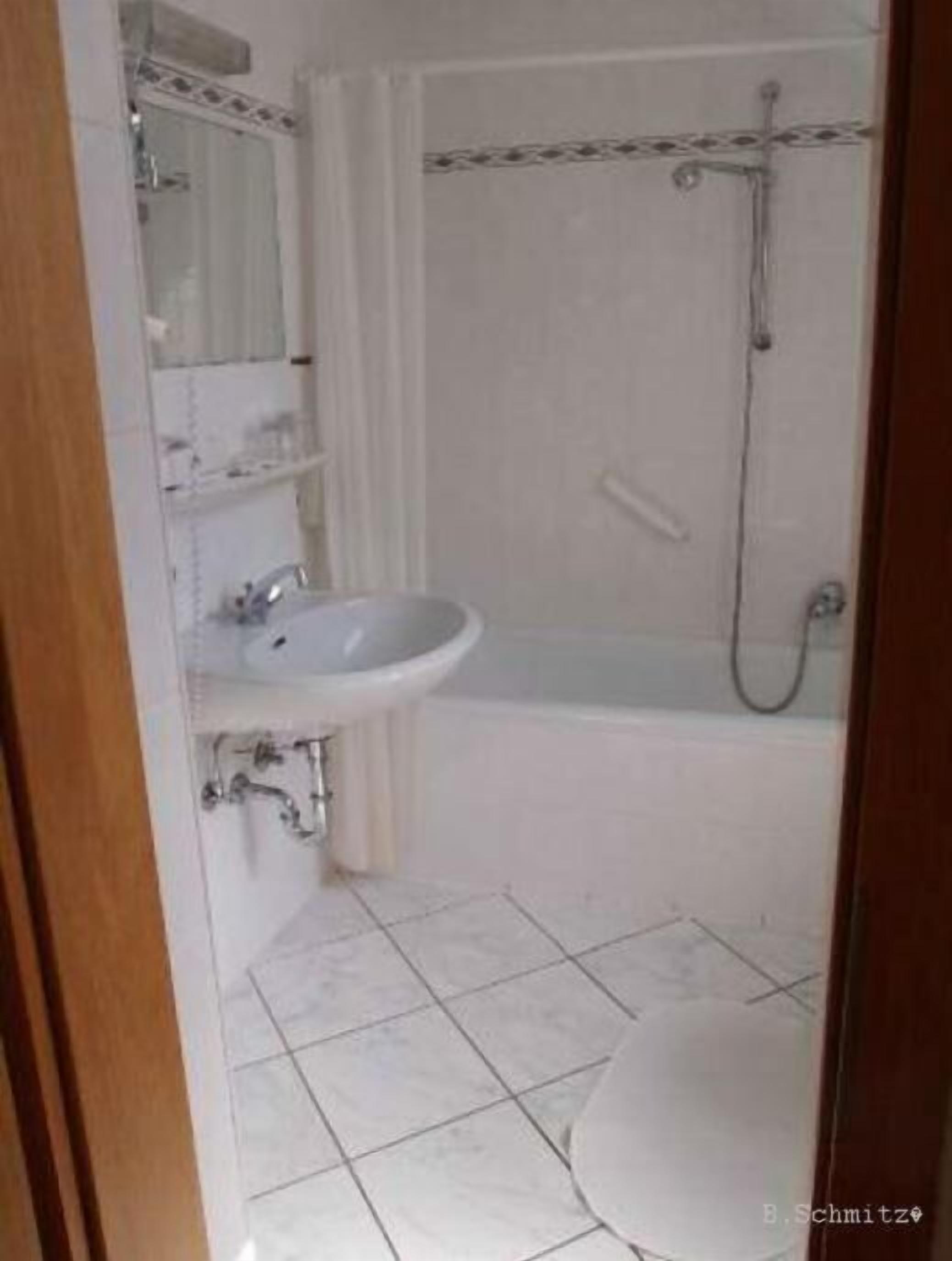 A bathroom with a sink, mirror, and shower.