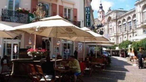 A hotel with outdoor seating and a large umbrella. - Hotel Am Friedrichsbad (Baden-Baden)