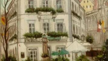 A building with a balcony, a fountain, and outdoor seating.