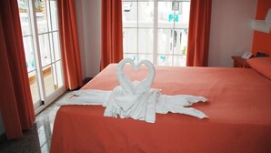 A hotel room with a bed, orange curtains, and a window with a view of the outside. - Mary Tere (Salobreña)