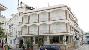 A multi-story building with balconies, a ground-level entrance, and a visible sign indicating a business establishment. - Mary Tere (Salobreña)