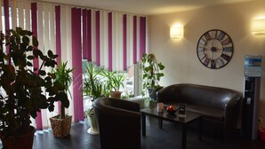 A living room with a sofa, a coffee table, and several potted plants. - Hotel Oyten am Markt (Oyten)