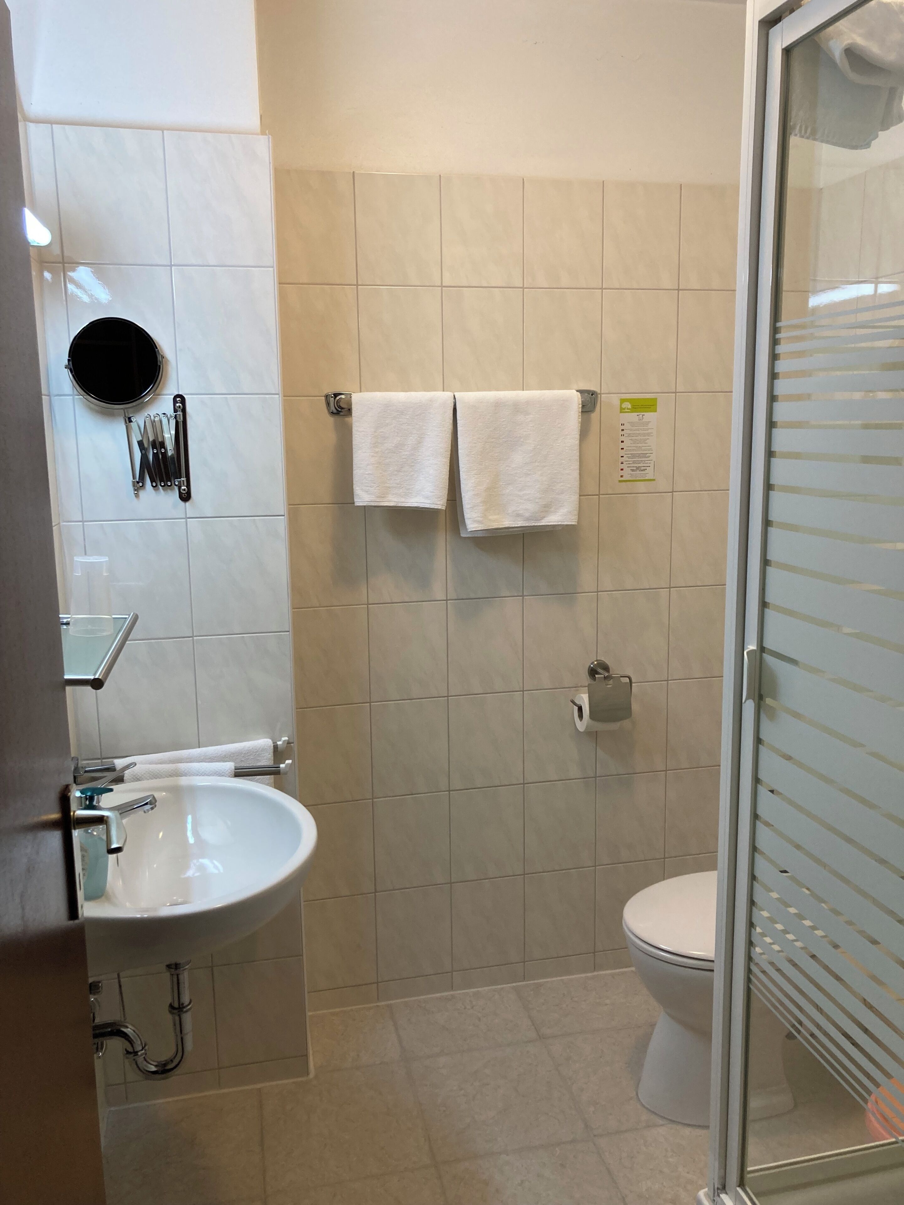 A bathroom with a white sink, a toilet, and a glass shower enclosure.