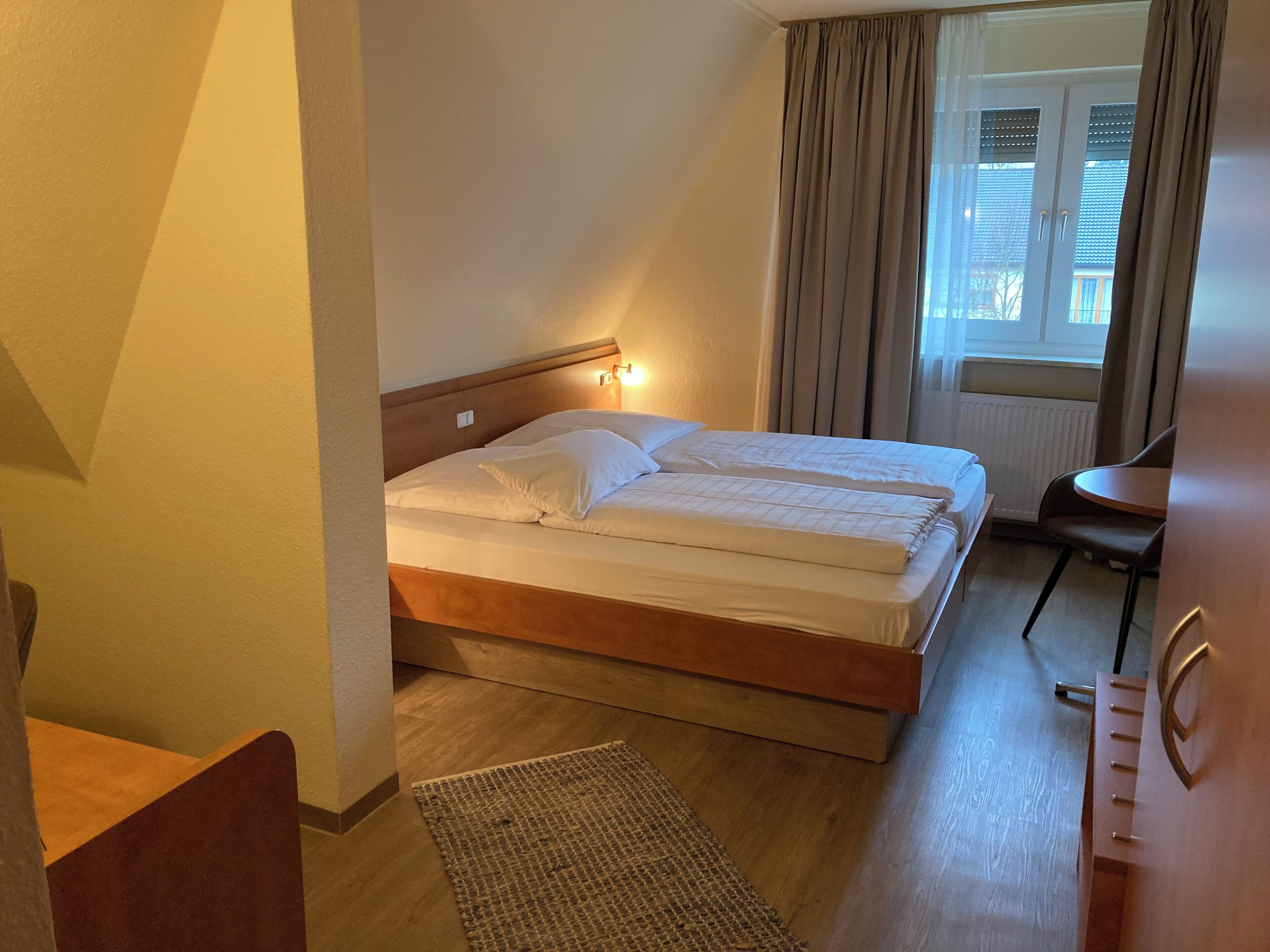 Ein Hotelzimmer mit einem Doppelbett, einem kleinen Tisch und einem Stuhl.