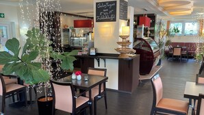 A restaurant with a bar area, seating arrangements, and a menu board. - Hotel Oyten am Markt (Oyten)