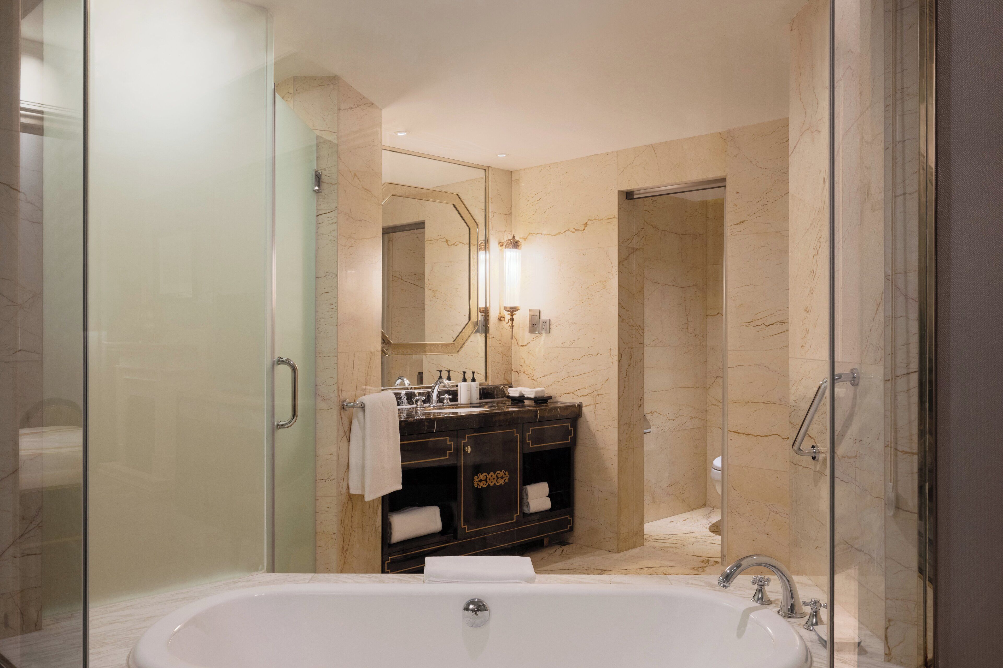 A modern bathroom with a glass-enclosed shower, a freestanding bathtub, and a vanity with a mirror.