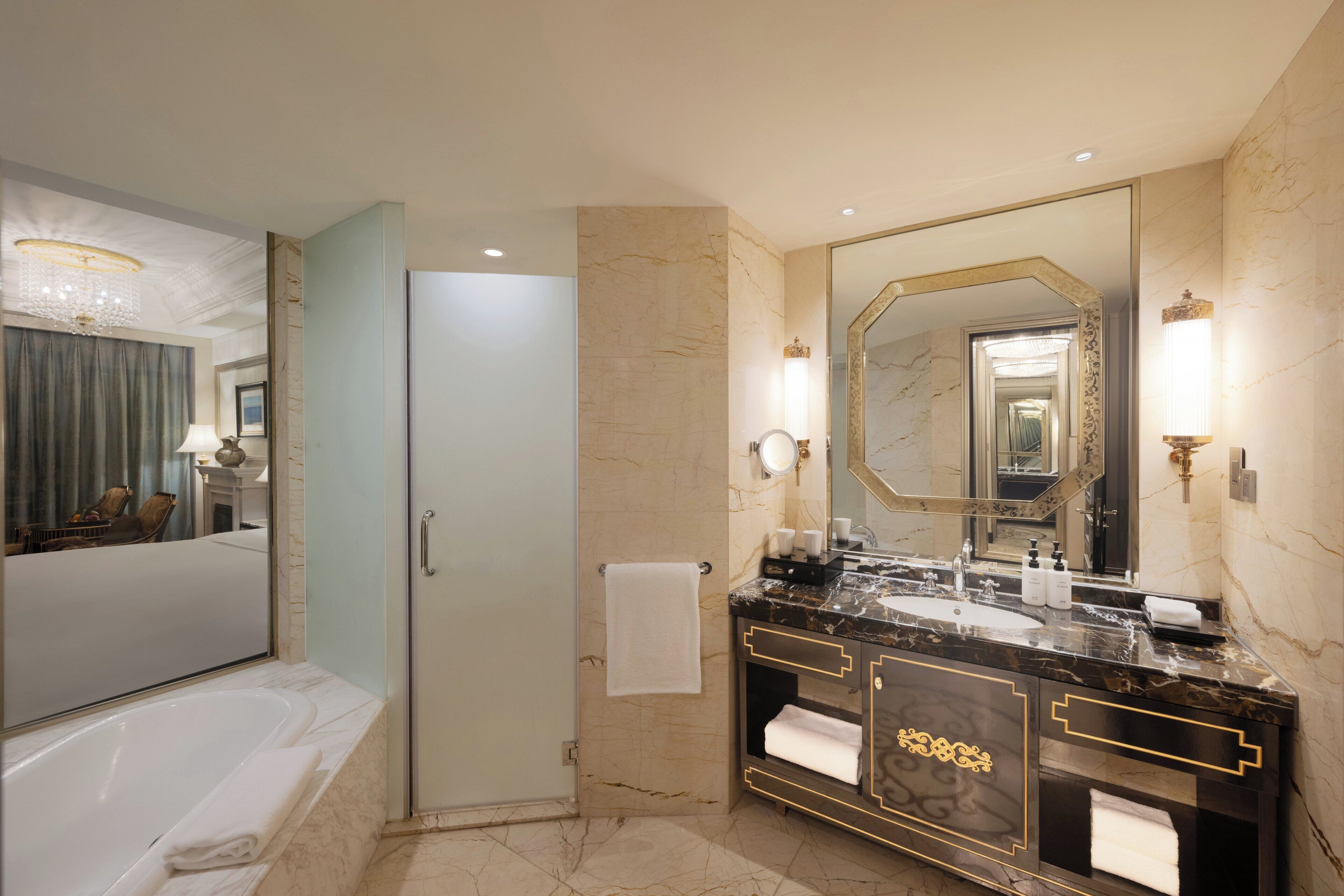 Un baño moderno con un espejo grande, una bañera y un tocador con encimera de mármol.