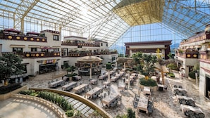 A spacious atrium with multiple levels, featuring outdoor seating areas, a central fountain, and a high glass ceiling. - Intercontinental Resort Lhasa Paradise by IHG (Lhasa)