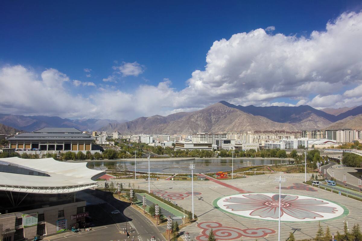 Um estádio com um grande desenho floral no campo, cercado por montanhas e um rio.