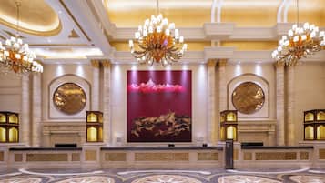 A grand lobby with ornate chandeliers, large circular mirrors, and a central artwork.