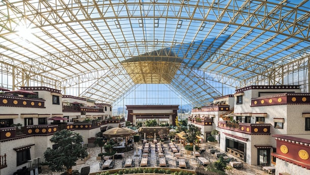 A spacious atrium with a high glass ceiling, multiple levels of balconies, and a central open area with seating. - Intercontinental Resort Lhasa Paradise by IHG (Lhasa)