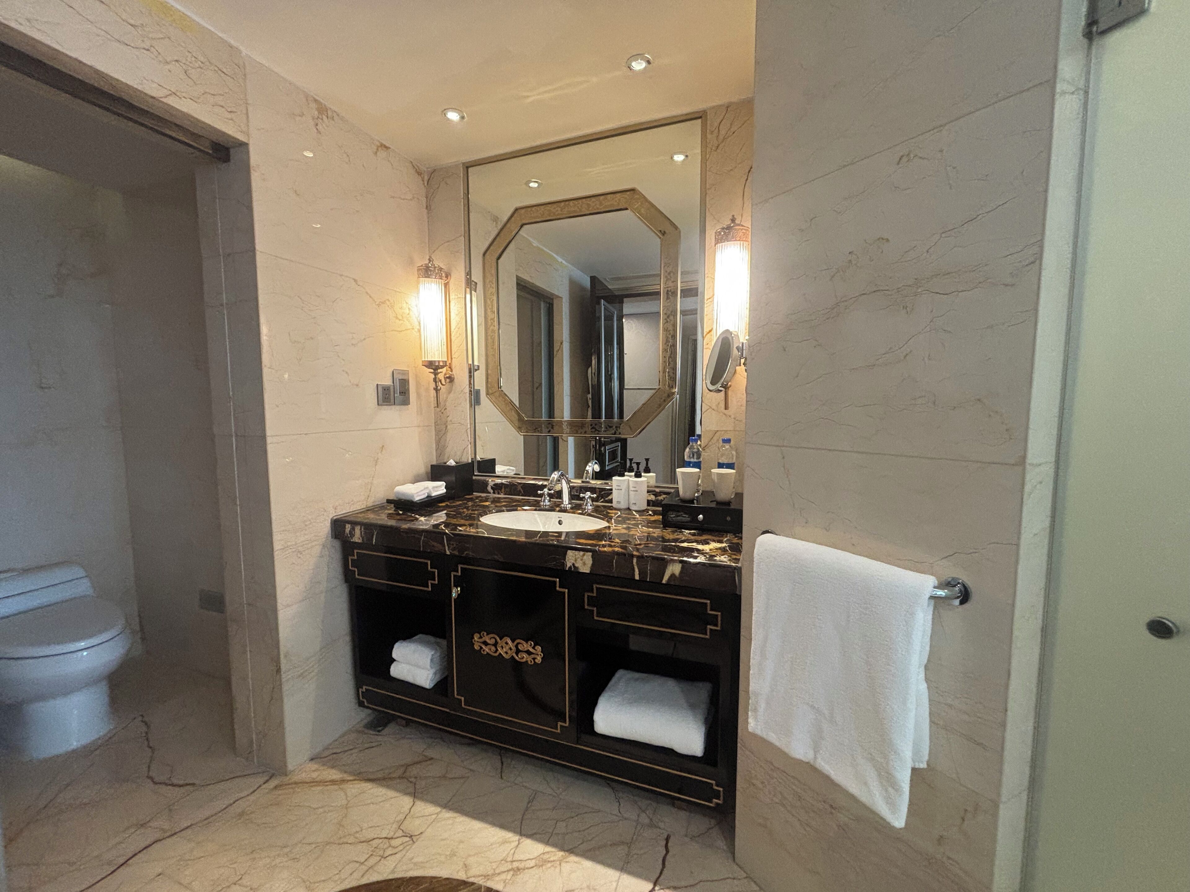A bathroom with a marble sink, a large mirror, and a towel rack.