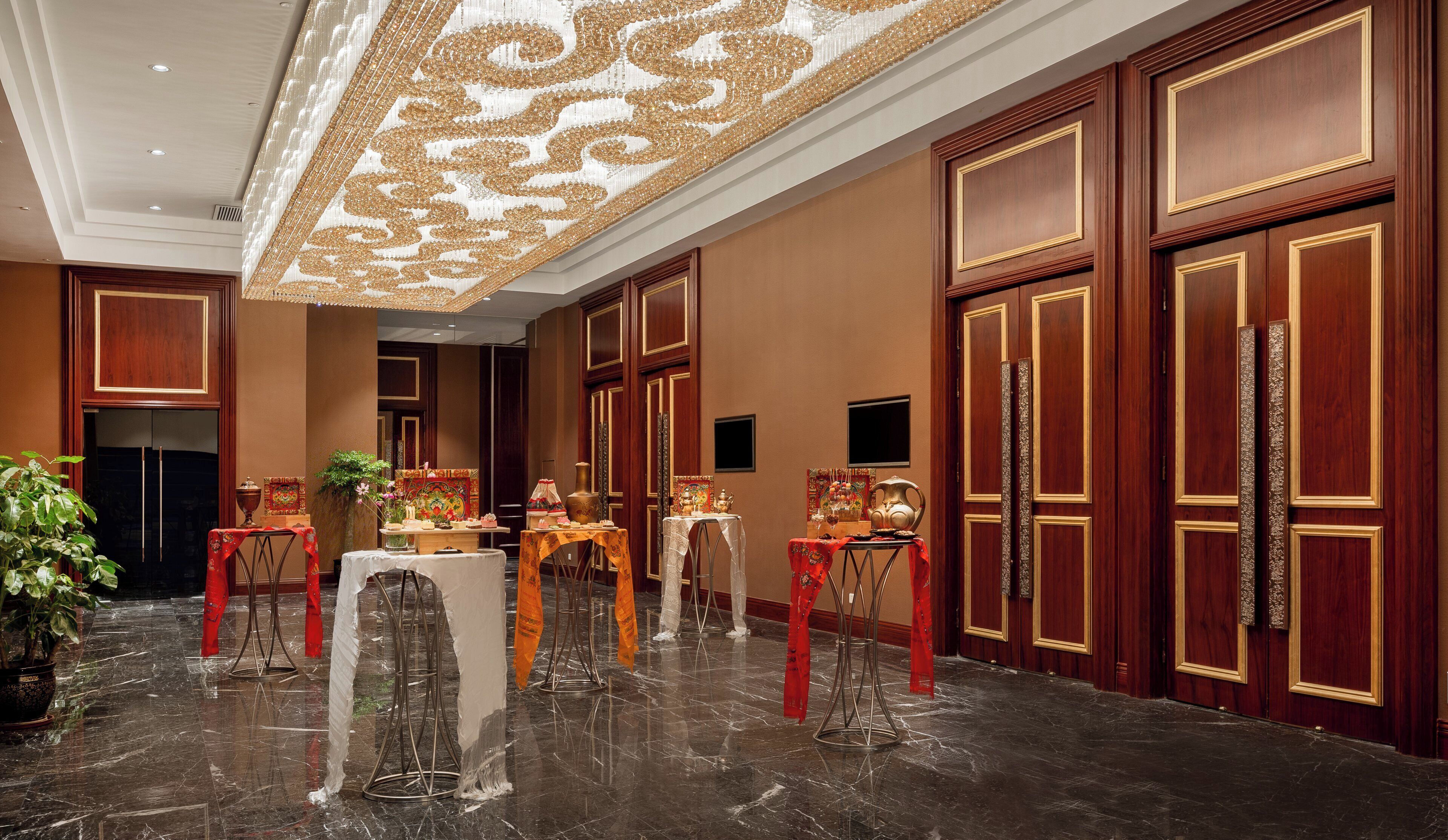 Un vestíbul d'hotel amb un paviment de marbre, panells de fusta i un sostre decoratiu.