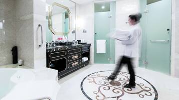 Un baño moderno con piso de mármol, un espejo grande, tocador negro y cabina de ducha con paredes de vidrio.