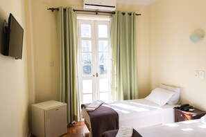 A hotel room with two beds, a small refrigerator, a bedside table with a lamp, and a TV mounted on the wall. - Hotel Carioca (Rio de Janeiro)